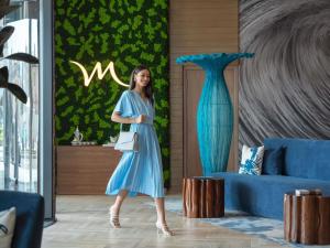 a woman in a blue dress standing next to a blue couch at Mercure Dubai Deira in Dubai