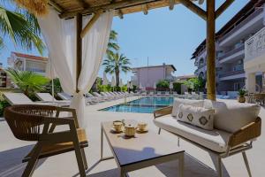 a patio with a table and chairs next to a pool at Hotel Tropical in Hanioti
