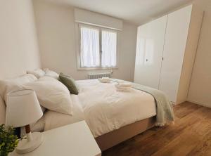 a bedroom with a large bed with white sheets and a window at Bassano Sweet Home in Bassano del Grappa