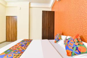 a bedroom with a white bed with colorful pillows at FabHotel Aqueens Plaza - Near Jawahar Circle, Patrika Gate in Siroli