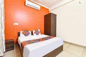 a bedroom with a large bed with an orange wall at FabHotel Aqueens Plaza - Near Jawahar Circle, Patrika Gate in Siroli