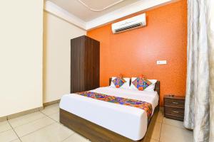 a bedroom with a bed and an orange wall at FabHotel Aqueens Plaza - Near Jawahar Circle, Patrika Gate in Siroli +32 photos