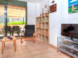 a living room with a chair and a television at Apartment Gardenia by Interhome in Lloret de Mar
