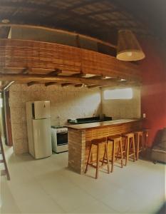 a kitchen with a counter with stools and a refrigerator at Sossego de Jaua in Camaçari +33 photos