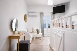 a white living room with a table and a mirror at White island rooms in Panteli
