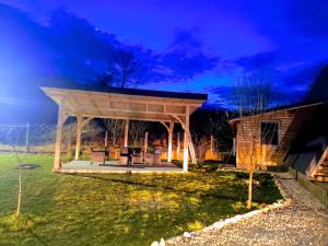 a pavilion with a picnic table in a yard at night at A Frame YRA cu ciubar in Câmpulung +5 photos