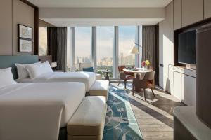a hotel room with two beds and a table at Mandarin Oriental Makati, Manila in Manila