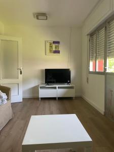 a living room with a white table and a tv at Casita San Simon in Bayón