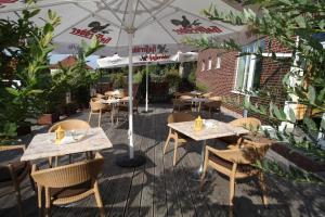 a patio with tables and chairs under an umbrella at Stadthotel Oranienburg in Oranienburg