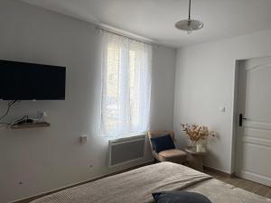 a bedroom with a bed and a tv on the wall at L'Opaline - Bord de Seine près de Giverny in Vernon