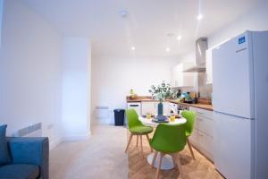 a kitchen with a table and green chairs at Derby Luxury Apartments - Curzon in Derby