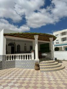 a white house with a porch and a staircase at villa Flamingo in Sousse