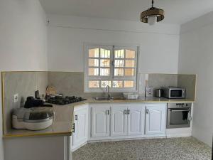 a kitchen with white cabinets and a sink at villa Flamingo in Sousse