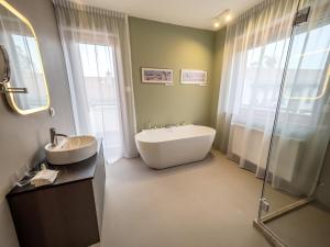a bathroom with a tub and a sink and a shower at Platán Villa - Platán Tata in Tata