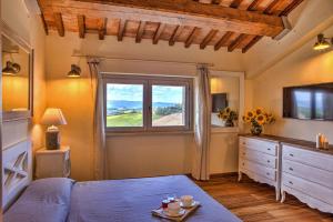 a bedroom with a bed and a window and a television at CASALE DEI GELSOMINI 8, Emma Villas in Todi