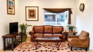 a living room with a leather couch and a tv at Tava Motel Manitou Springs in Manitou Springs