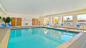 a large swimming pool with blue chairs in a building at Tava Motel Manitou Springs in Manitou Springs