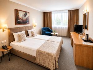 a hotel room with a large bed and a desk at Hotel Orbita in Varna City +61 photos
