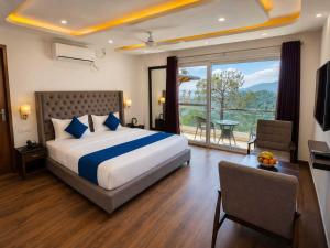 a bedroom with a large bed and a large window at Hotel The Girnaar Near Valley View Dharampur Kasauli Road in Dharampur