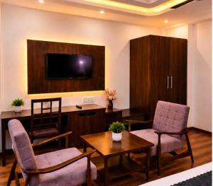 a living room with two chairs and a table and a tv at Hotel The Girnaar Near Valley View Dharampur Kasauli Road in Dharampur +17 photos