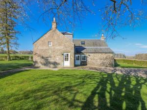 an exterior view of a stone house with a green yard at Meadowgreen Farmhouse in Forfar