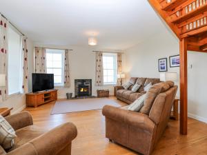 a living room with a couch and a tv at Meadowgreen Farmhouse in Forfar