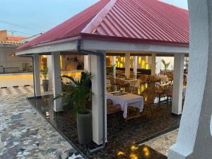 a restaurant with tables and chairs and a red roof at Hôtel villa blanca in Lomé