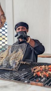 a man is cooking food on a grill at Hôtel villa blanca in Lomé