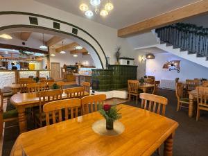 a restaurant with wooden tables and wooden chairs at Spa Hotel Podlesí - Walldorf a Pohádková vesnička in Podlesí