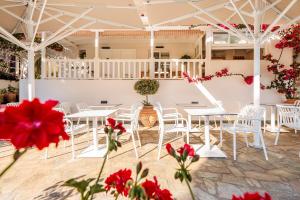 a room with white tables and white chairs and red flowers at Casa Nina in Patitiri +133 photos