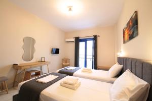 a room with two beds and a desk and a window at Mochlos Studios in Mochlos