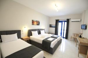 a hotel room with two beds and a desk at Mochlos Studios in Mochlos