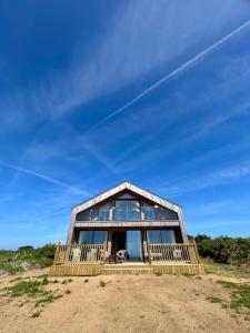 a wooden house with glass windows on a beach at Pourquoi Pas B&B in Sark