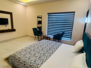 a bedroom with a bed and two chairs and a window at Mount Green Hotel Bharatgarh in Bharatgarh