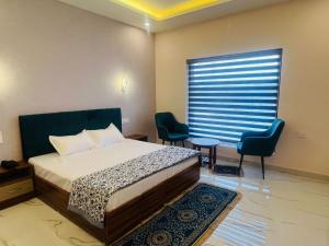a bedroom with a bed and two chairs and a window at Mount Green Hotel Bharatgarh in Bharatgarh