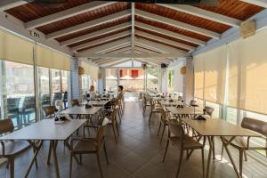a dining room with tables and chairs and windows at Spyridoula Resort in Corfu in Gouvia
