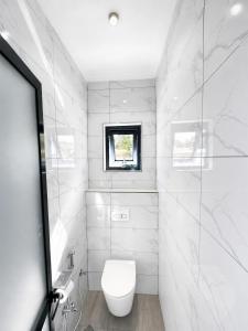 a white bathroom with a toilet and a window at Mama Thea homes in Moshi +74 photos