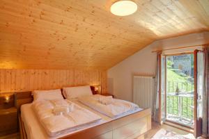 a bed in a wooden room with a window at Ca Contina in Val Verzasca - Happy Rentals in Frasco