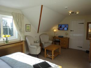 a bedroom with a bed and two chairs and a table at Hunters Croft in Sway