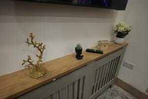 a wooden counter with flowers and a remote control on it at Deaf Property - Woolwich Elizabeth Line Studios in Woolwich