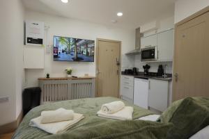 a kitchen with two towels sitting on a bed at Deaf Property - Woolwich Elizabeth Line Studios in Woolwich