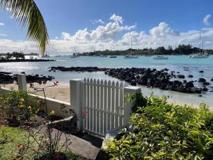 a white fence on a beach with boats in the water at Résidence îlot in Grand-Baie +15 photos
