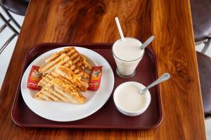 a tray with a plate of waffles and a glass of milk at The Whistling Pine Homestay With Natural Swimming Pool in Lansdowne