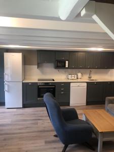 a kitchen with black cabinets and a blue chair at Wells House & Gardens Self Catering 3 Bedrooms & Sofa Bed Sleep8 in Glenranny