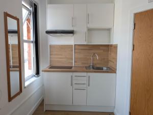 a kitchen with white cabinets and a sink at Oscar Lodge in Northampton