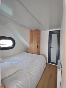 a bedroom with a large white bed and a window at Bateau Lac du Der - Nuisement - Navigation in Les Petites-Côtes