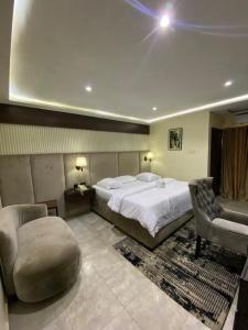 a bedroom with a large bed and a couch and a chair at Wesley Hotels in Benin City