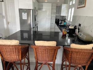 a kitchen with a counter with three bar stools at Résidence îlot in Grand-Baie