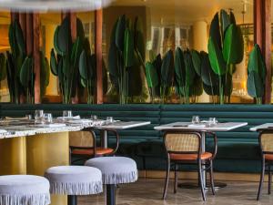a restaurant with tables and chairs and a painting of plants at Gem Forest Hotel Nairobi - MGallery Collection in Nairobi