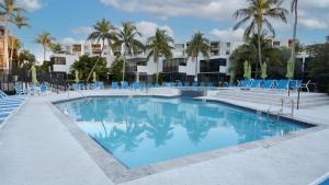 a swimming pool with blue chairs and palm trees at B307 Moon Bay in Villa Verde